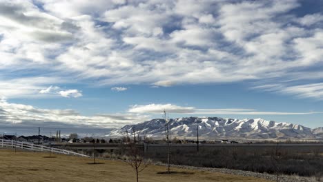 Cloudscape-over-a-distant-snowy-mountain-across-the-urban-valley---static-time-lapse