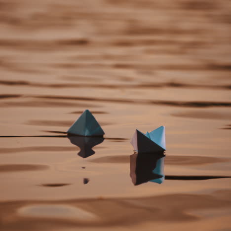 evening water background and two paper boats swimming. homemade origami ships floating on beautiful water surface.
