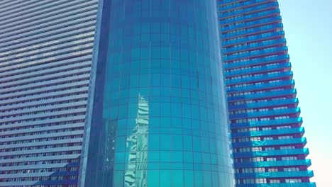 shot of reflections of sun, clouds and sky on glass windows of city skyscraper.