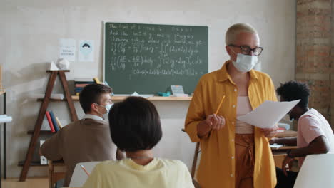 mujer con máscara enseñando a los estudiantes durante la pandemia