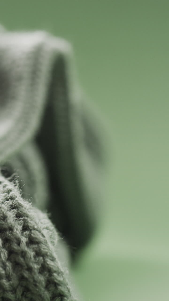 Micro vertical video of close up of green wooly knitted fabric with copy space on green background