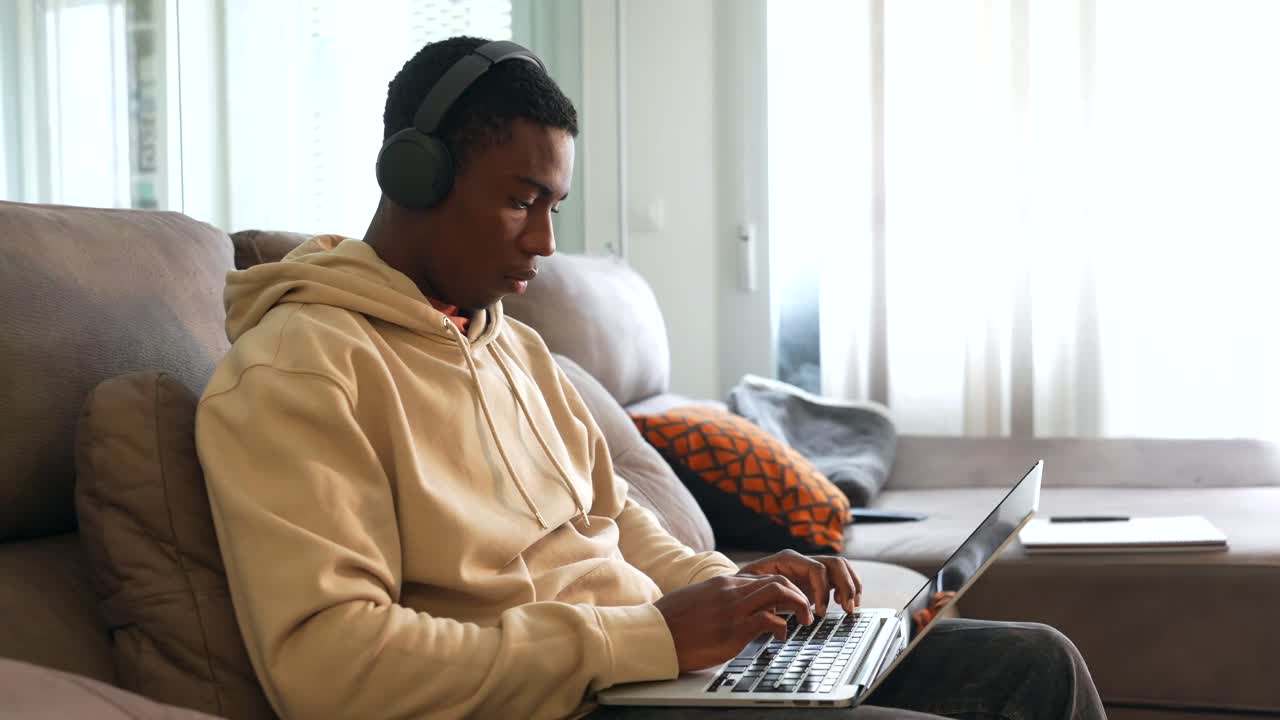 Man using laptop on couch with headphones