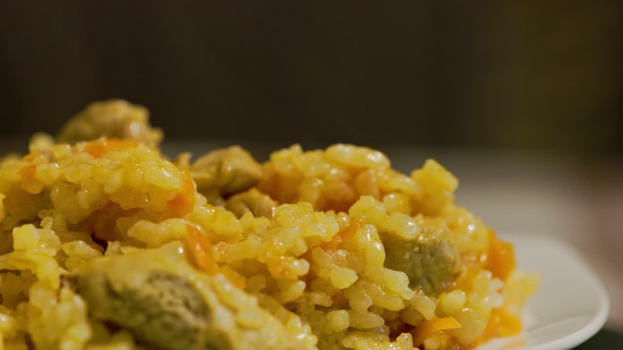 plato de pilaf caliente, pilau, pilaw o pilaf con carne de pavo girando en el plato