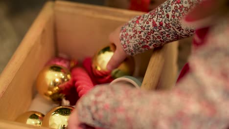 child playing with christmas ornaments in a wooden box