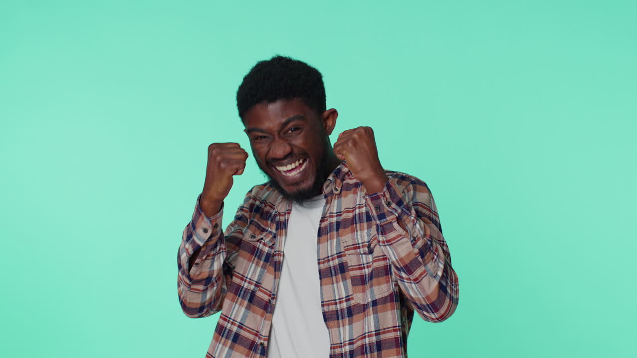 African american man shouting, raising fists in gesture I did it, celebrating success, winning