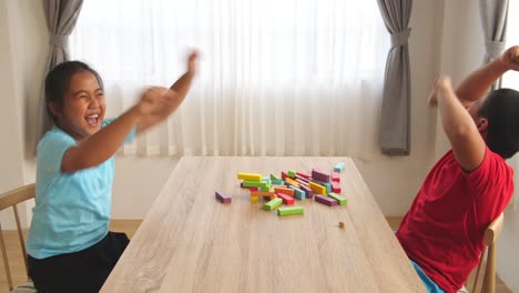 asian children play wood block tower game and falling block