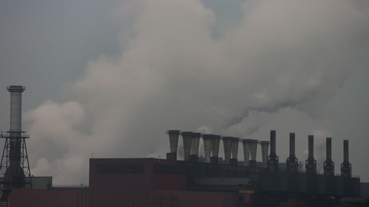 Industrial chimneys at a power plant releasing white smoke in the air