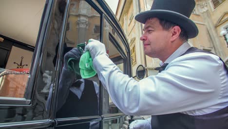 close up of man wipes a small ornament on the side of a ford model t car