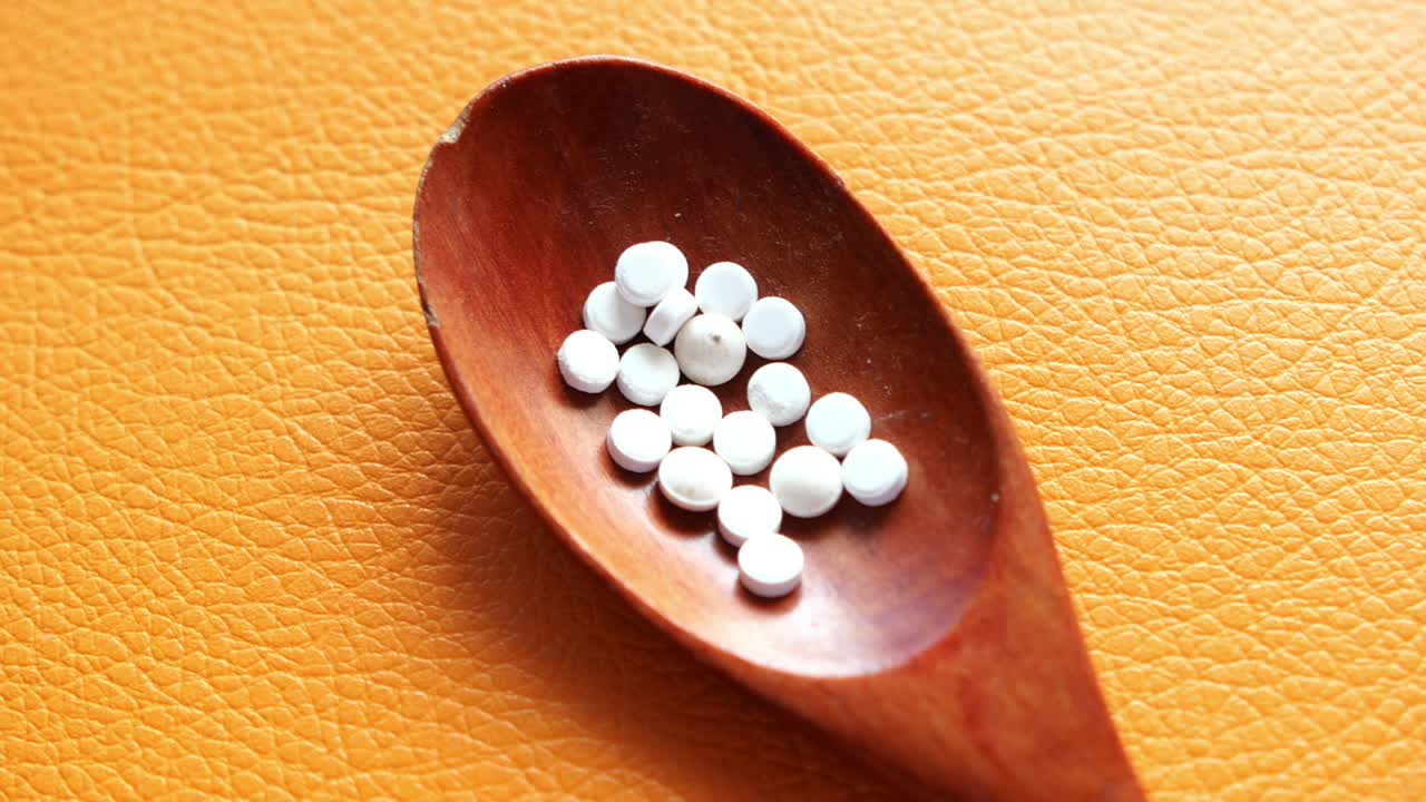 pastillas blancas en cuchara de madera
