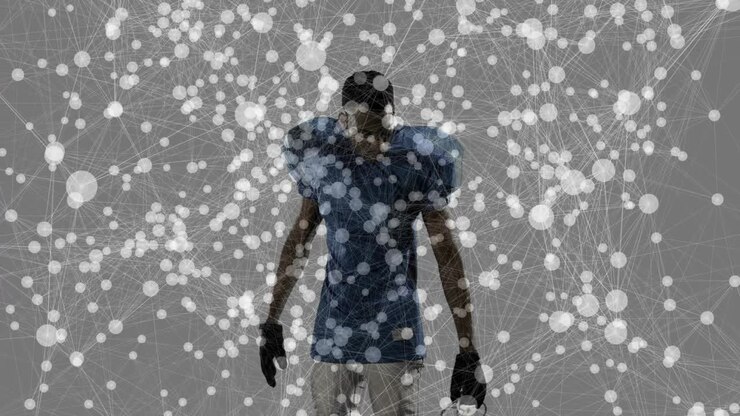 Football player holding helmet at side, securing chin strap for safety amid drifting particles