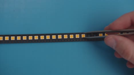 manually picking leds with tweezers from a black strip blue background