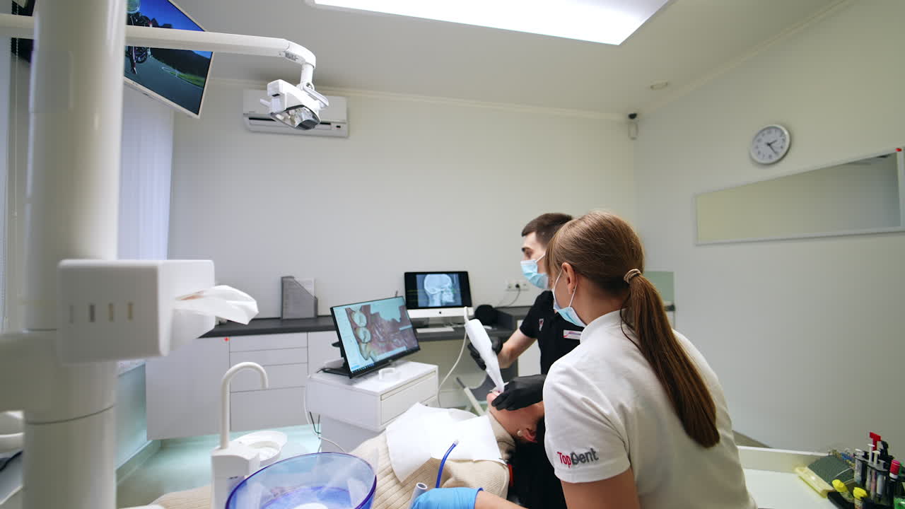 Professional dentist using the camera to take a video of patient's teeth. Spacious office with modern equipment in dental clinics.