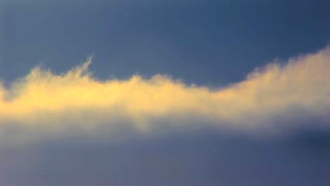 time lapse shot of sun lit clouds moving beneath a blue sky