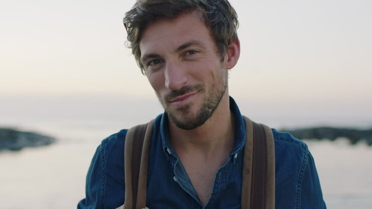 ritratto di un attraente affascinante uomo caucasico sorridente flirtante sicuro di sé sulla tranquilla spiaggia costiera