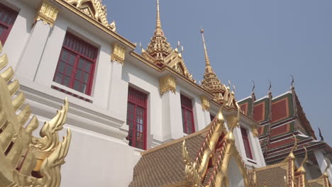 walking under a gold and white buddhist temple pointing up of a popular travel destination in the city of bangkok in thailand