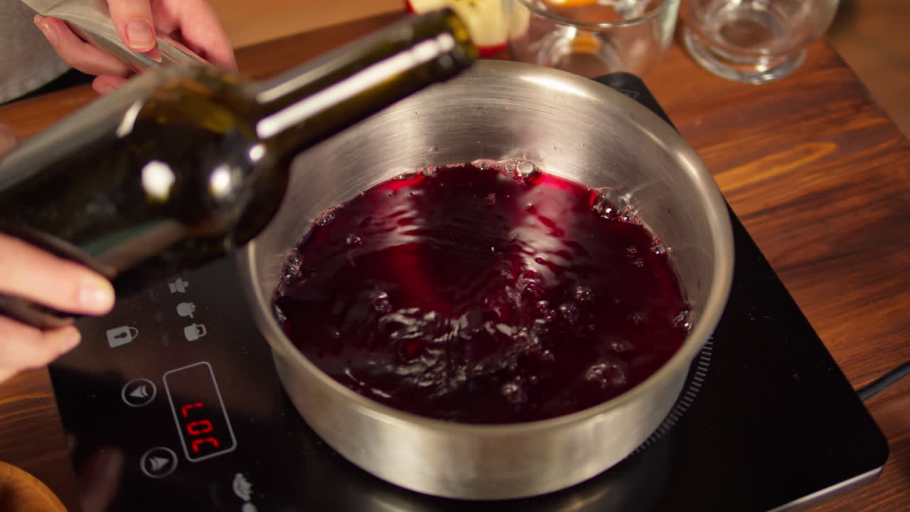 Preparazione del vin brulé versando vino rosso e aggiungendo spezie.