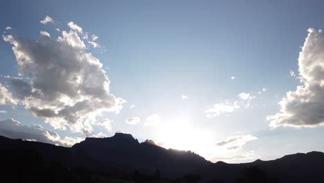 impresionante hiperlapso de tiempo de la puesta de sol detrás del pico de los dragones, montañas drakensberg, sudáfrica, destello de lente, nubes rodantes, rayos de sol