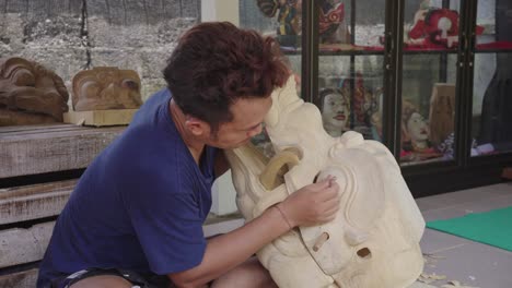 indonesian artist polishing his wooden barong mask work