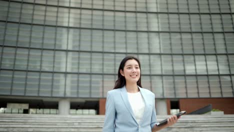 hermosa mujer de negocios con tableta caminando en el pasillo entre los edificios en el centro de la ciudad. mujeres confiadas caminan hacia sus objetivos para el éxito en la ciudad.