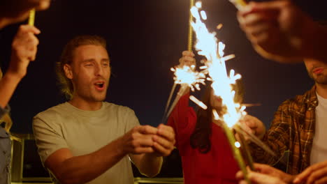 Multiethnic-friends-enjoying-birthday-party-on-roof.-People-burning-sparklers.