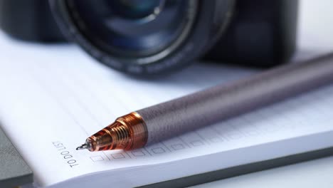 notepad, pen and camera on table