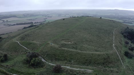 AERIAL---South-Downs-Way-and-hill,-East-Sussex,-United-Kingdom,-wide-rising-shot