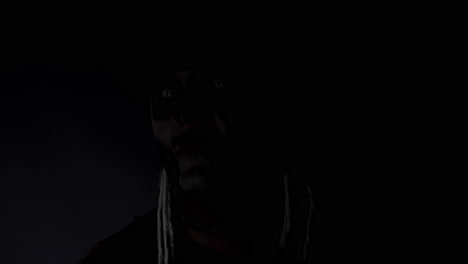 creepy man with skeleton makeup appearing from darkness when light falls on him, making faces