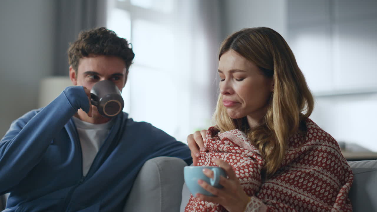 Domestic couple drinking tea feeling cold at home closeup. Man woman talking