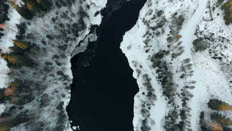 aerial, birdseye, top down, drone shot, above a river, surrounded by leafless forest and first snow on the ground, near joensuu, north karelia, finland