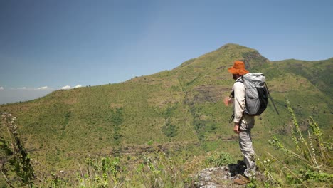 un excursionista occidental en áfrica oriental mira hacia un valle sobre una montaña tropical