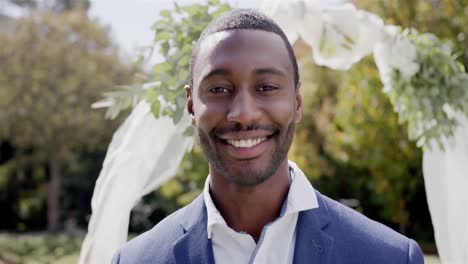 Portrait-of-happy-african-american-groom-smiling-at-wedding-ceremony-in-sunny-garden,-in-slow-motion