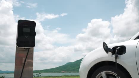 Progressive-concept-of-EV-car-with-green-field,-hill-and-lake-as-background.