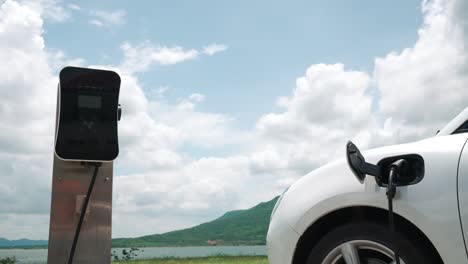 progressive concept of ev car with green field, hill and lake as background.