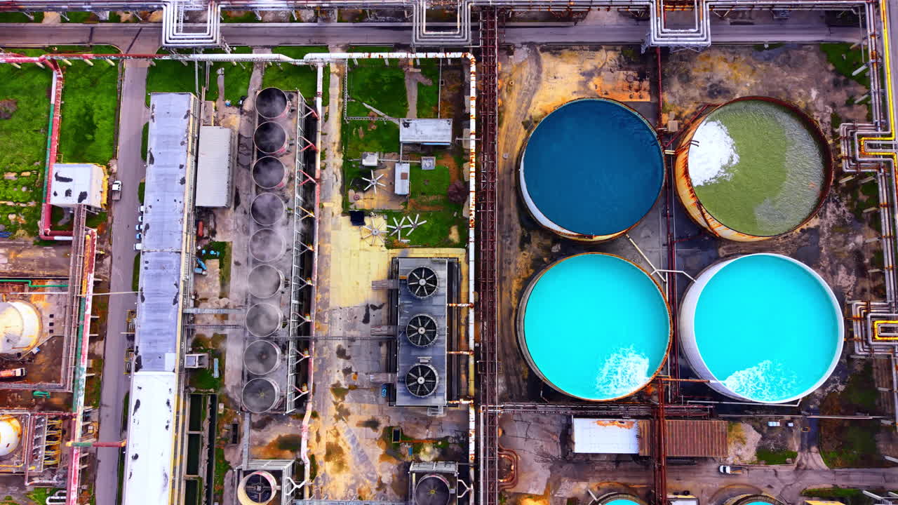 Circular blue water tanks and cooling towers at a large chemical factory. Aerial view of industrial water treatment plant facility