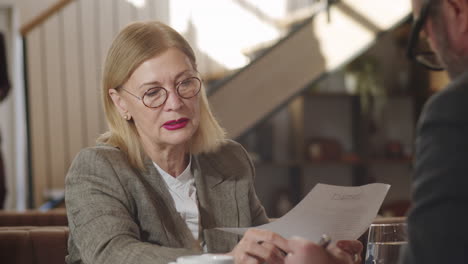 senior business lady discussing contract with partner in restaurant