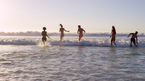 Eine-Vielfältige-Gruppe-Von-Freunden-Schwimmt-Bei-Sonnenuntergang-Im-Meer