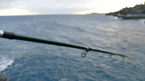 person fishing with a rod and reel by the sea