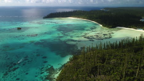 the isle of pines and the crystal clear water of oro's bay as a boat sales out - aerial flyover