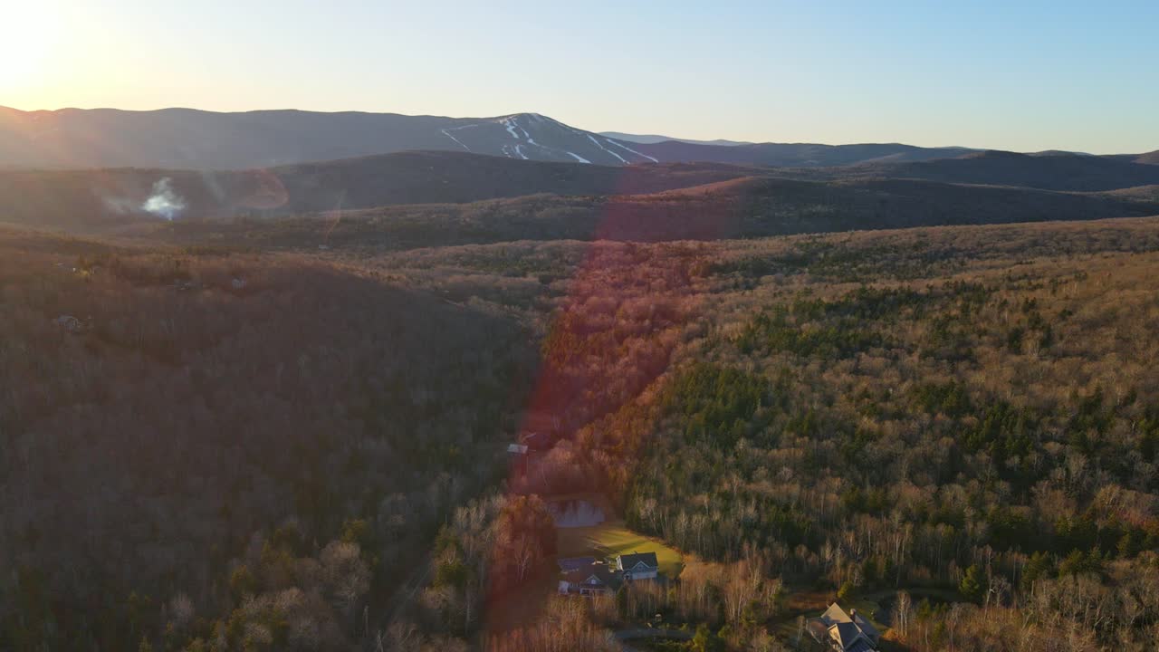 un dron filmado en vermont del invierno y las montañas de esquí en el fondo durante la puesta de sol