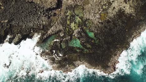 bird's eye view of waves crashing on the makapu'u tidepools off of the rocky coast of oahu, hawaii