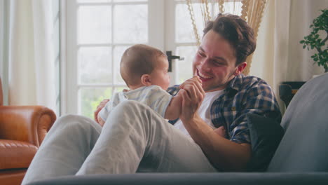 Loving-Transgender-Father-Playing-With-Baby-Son-Sitting-On-Sofa-At-Home