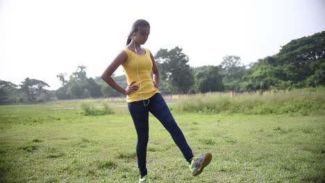 teenage young girl doing yoga and morning exercise at sunrise on ground listening to music with earphone