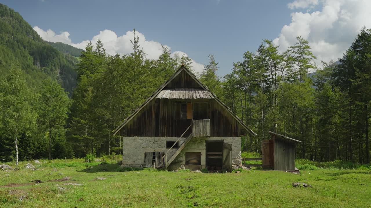 Old rustic barn in the scenic Robanov Kot valley surrounded by lush forest and mountains