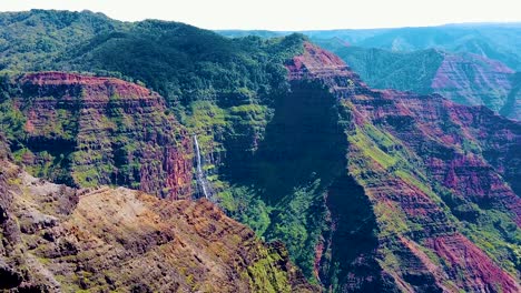 hd hawaii kauai slow motion boom down from waimea canyon with a waterfall in the distance to tall grass