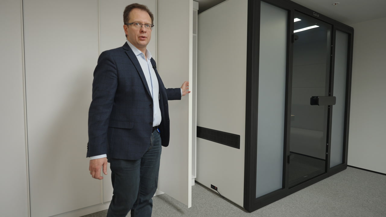 Caucasian Businessman Opens Hidden Storage Next To Glass Pod, Gesturing As Facility Manager During Office. Creative