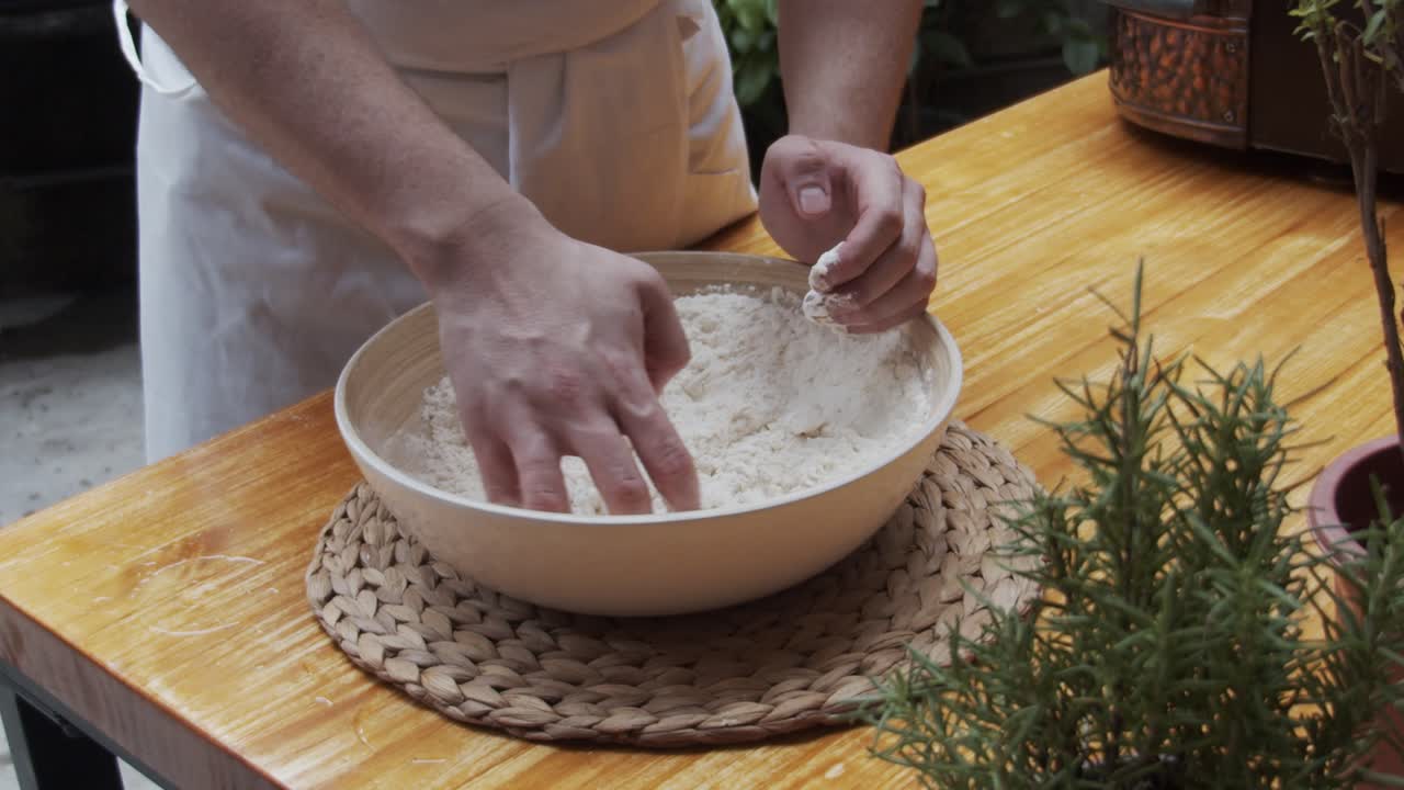 주방장은 피자 반죽을 나무 테이블에 있는 깊은 접시에 담습니다.