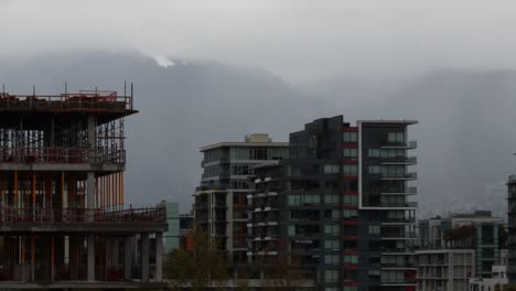 timelapse of building in vancouver downtown with mountains and clouds