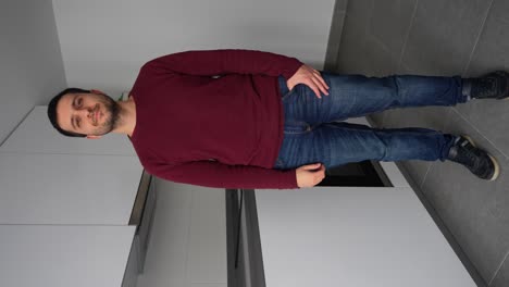 smiling man looks at camera showing a thumb up in a sign of approval in modern empty grey white kitchen