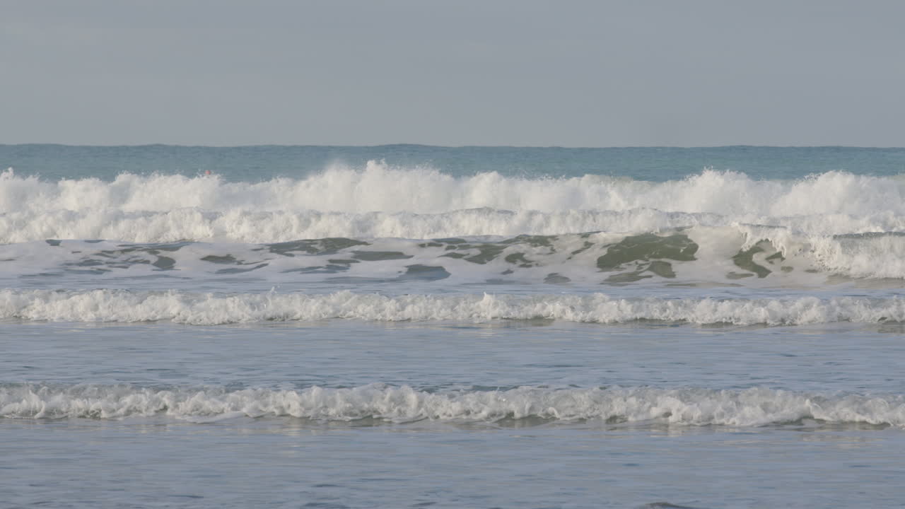Pan shot over a group of surfers waiting for waves in Castle Point Beach, New Zealand