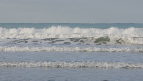 Toma-Panorámica-Sobre-Un-Grupo-De-Surfistas-Esperando-Olas-En-Castle-Point-Beach,-Nueva-Zelanda